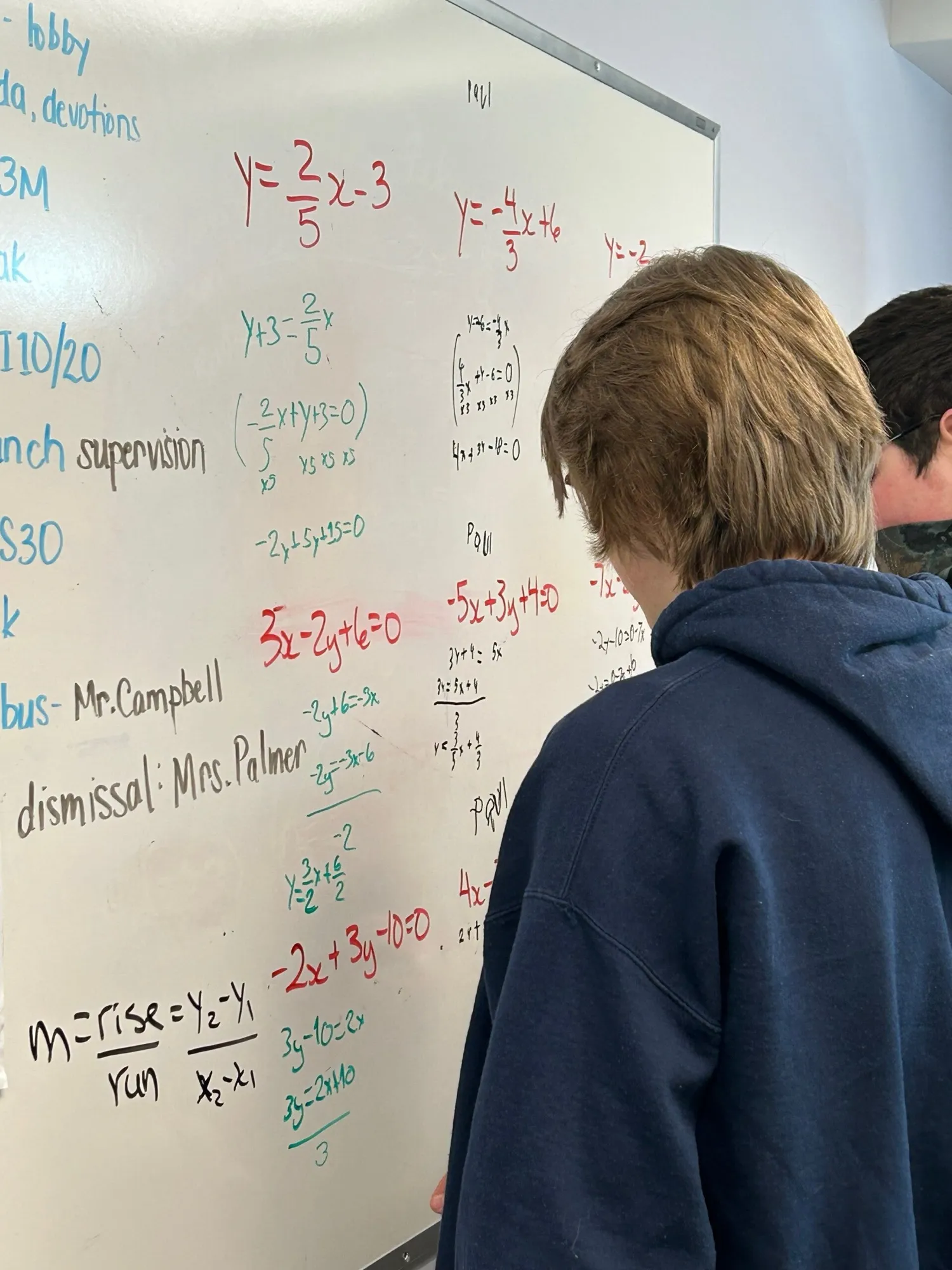 A student working through equations on a classroom whiteboard